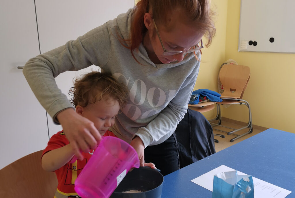 Erwachsene Person hilft Kleinkind beim Backen