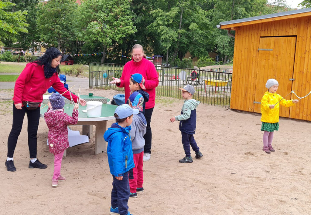 Kinder spielen im Freien unter Aufsicht von Erwachsenen