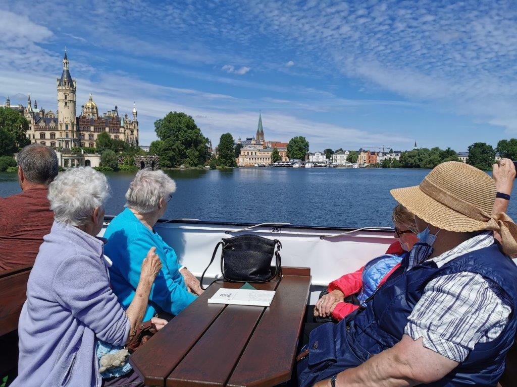 Gruppe älterer Menschen auf einer Bootstour mit Blick auf das Schweriner Schloss