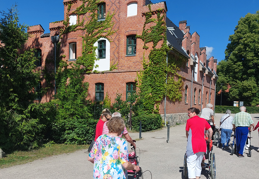 Gruppe von älteren Menschen vor einem alten Backsteingebäude