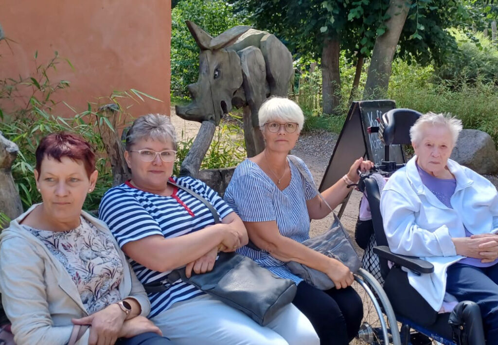 Vier Personen sitzen in einem Garten.