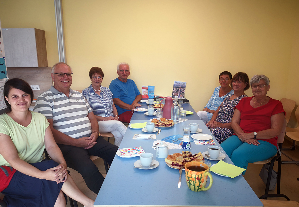 Eine Gruppe von Menschen sitzt lächelnd um einen Tisch.