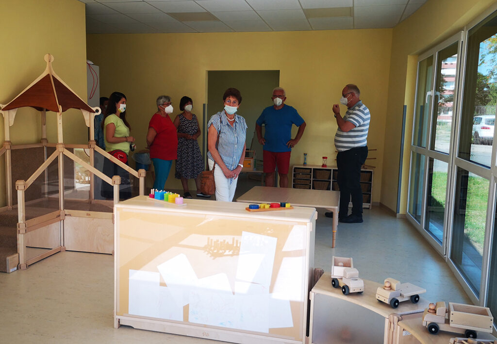 Eine Gruppe von Menschen steht in einem Raum mit Kinderspielzeug.