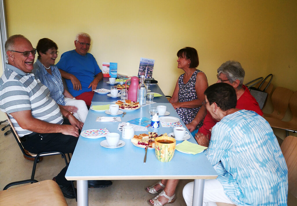 Gruppe von Menschen, die um einen Tisch sitzen und lachen.