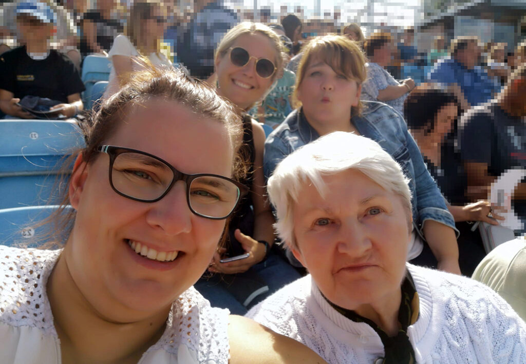Vier Frauen in einem Stadion, l&auml;chelnd in die Kamera blickend.