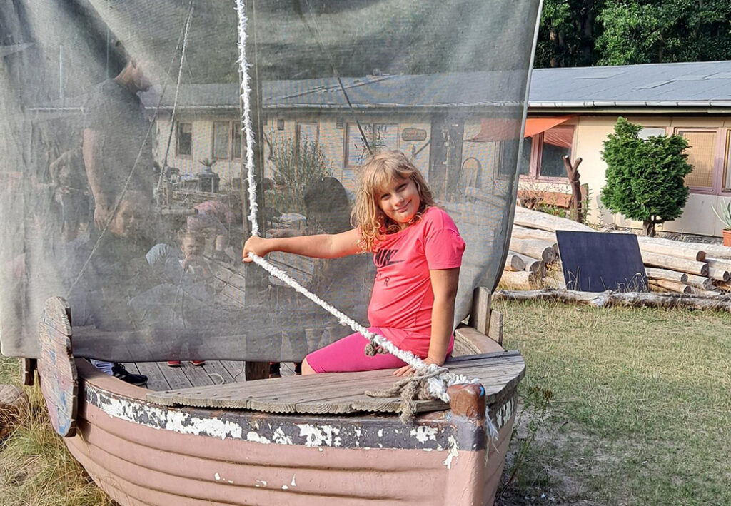 Ein M&auml;dchen sitzt in einem Spielschiff und h&auml;lt ein Seil.