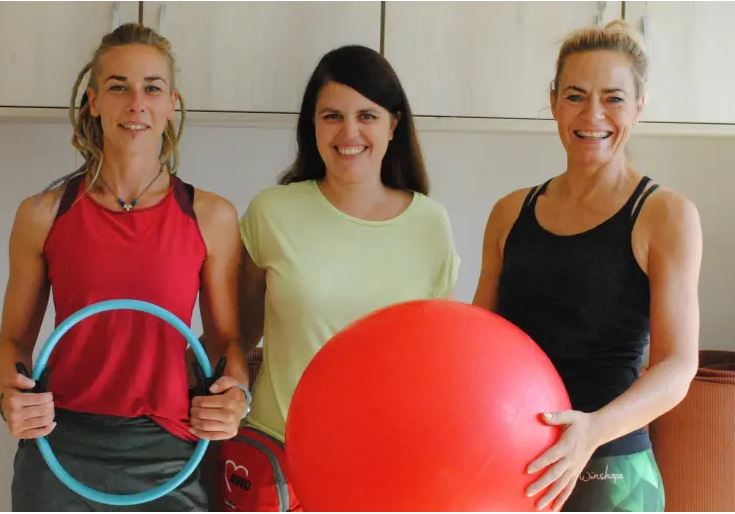 Drei Frauen posieren mit Sportgeräten.