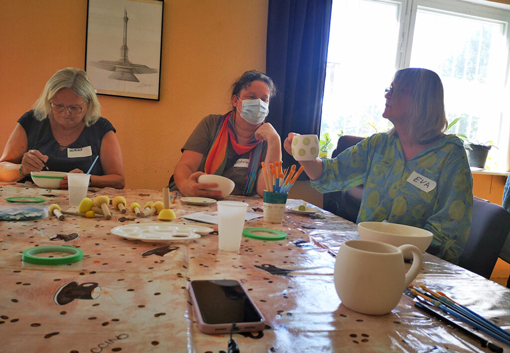 Personen bei einem Keramik-Workshop mit Farben und Pinseln