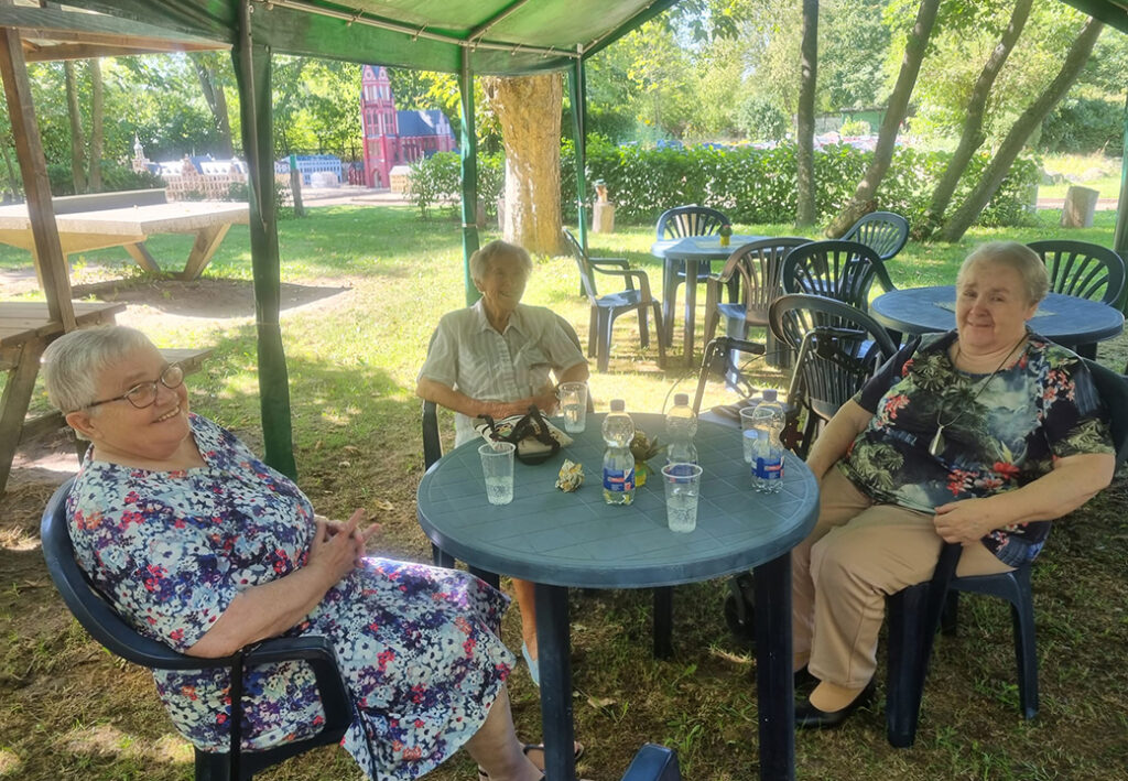 Drei ältere Frauen sitzen an einem Tisch im Freien