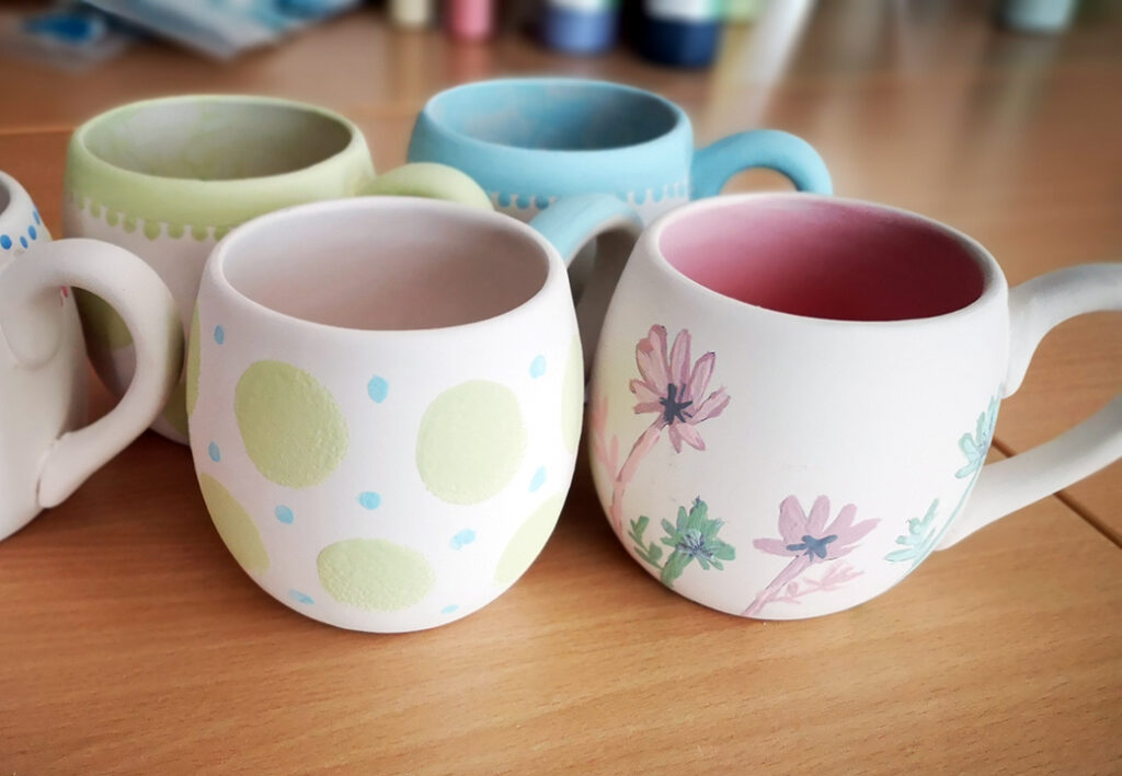 Verschiedene handbemalte Tassen auf einem Tisch.