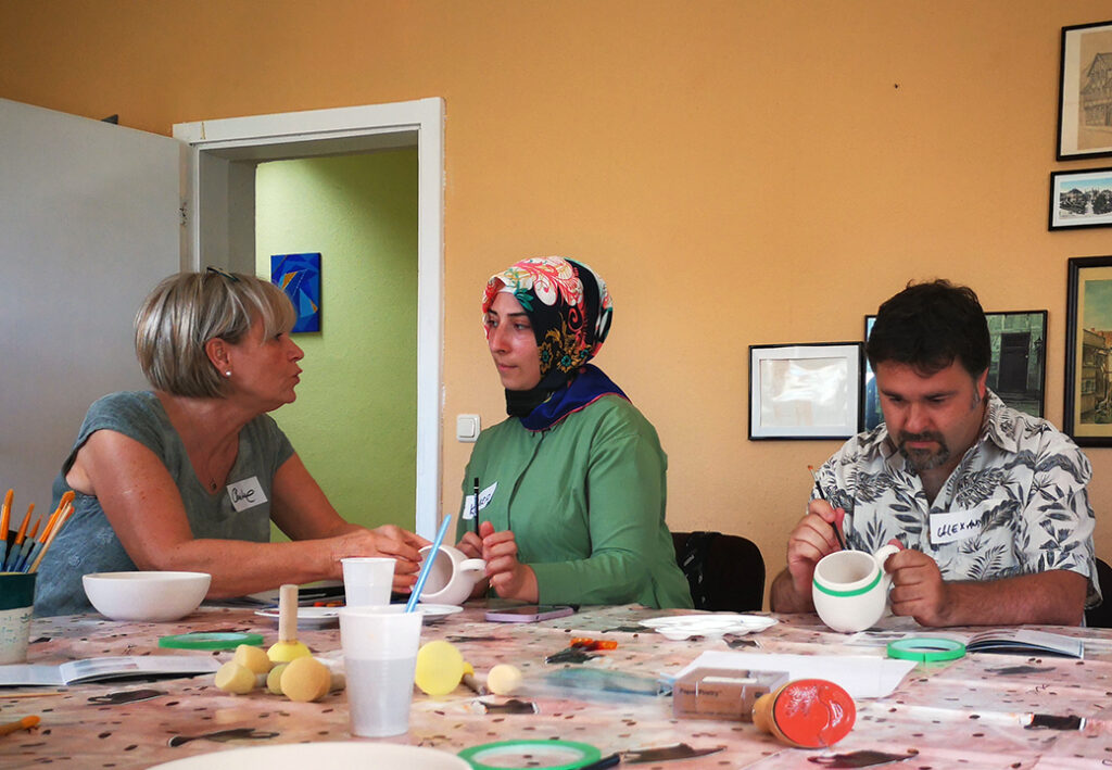 Drei Personen bei einem Kunst-Workshop am Tisch sitzend