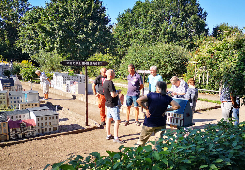 Menschen stehen in einem Miniaturpark mit einem Schild mit der Aufschrift 'Mecklenburg'.
