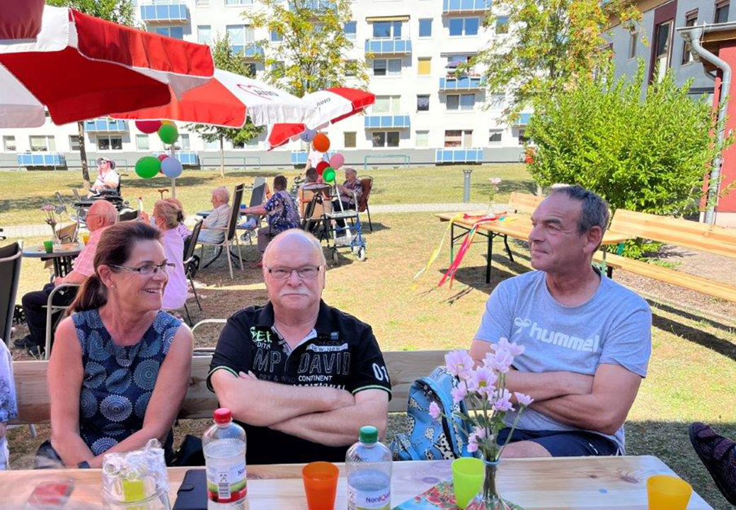 Eine Gruppe von Menschen sitzt draußen an einem Tisch während einer Veranstaltung.