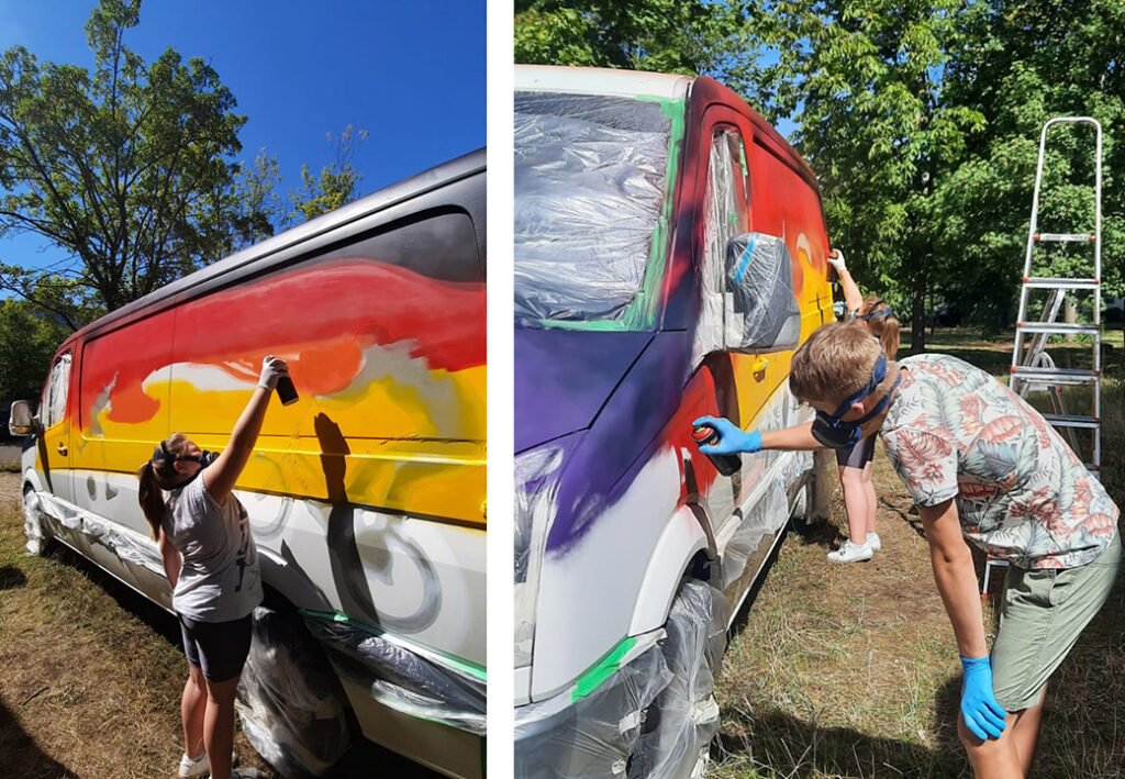 Zwei junge Menschen bemalen einen Transporter mit Graffiti im Freien.