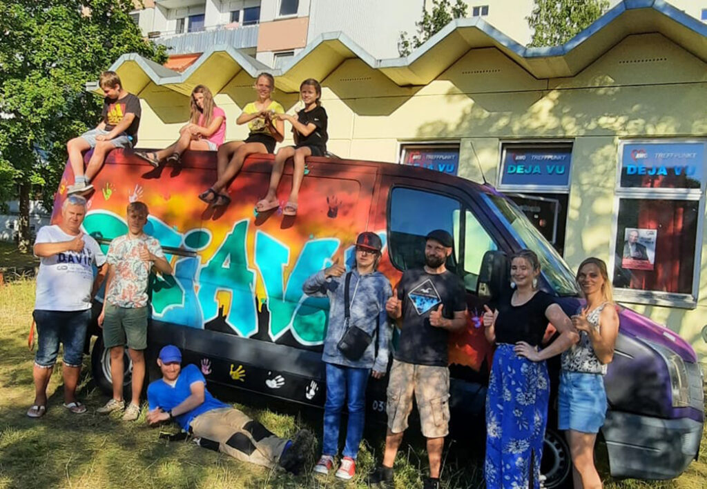 Leute posieren vor einem bunt bemalten Van der AWO.