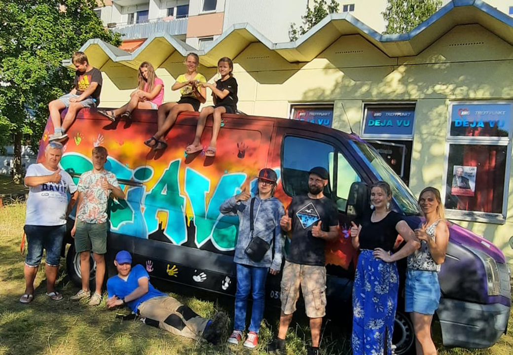 Leute posieren vor einem bunt bemalten Van der AWO.