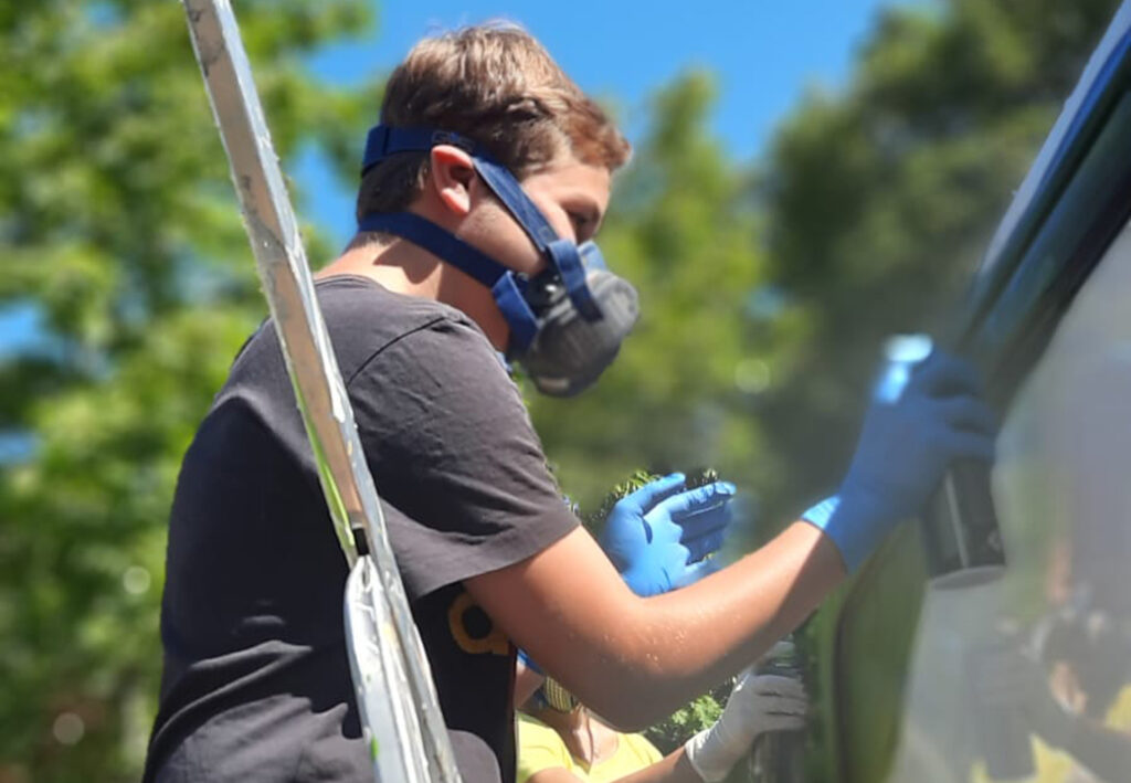 Person spr&uuml;ht Farbe auf ein Objekt