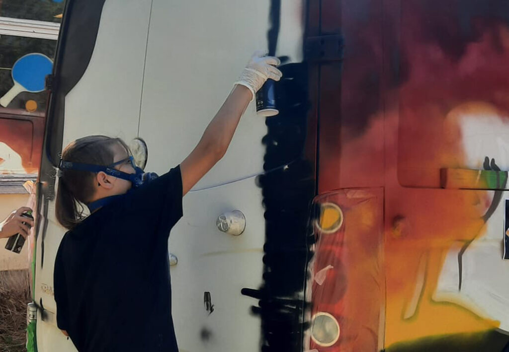 Person bespr&uuml;ht Wand mit Farbspray