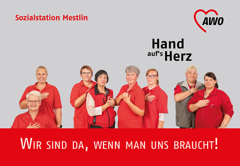 Gruppe von AWO-Mitarbeiterinnen in roten Kleidungsstücken mit der Hand auf dem Herzen.