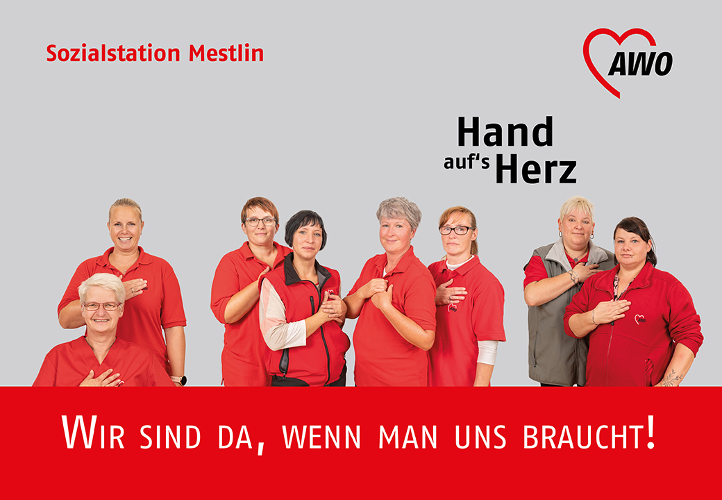 Gruppe von AWO-Mitarbeiterinnen in roten Kleidungsstücken mit der Hand auf dem Herzen.