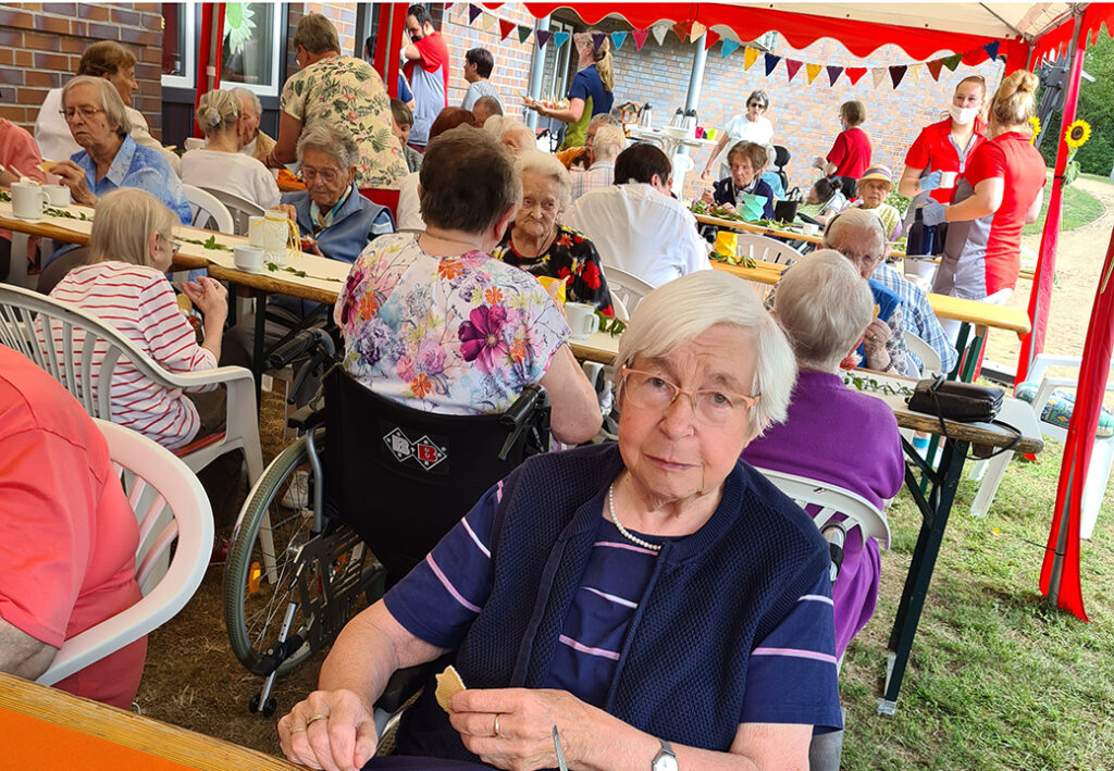 Ein gruppenbild von Menschen, die bei einem sozialen Event im Freien an einer langen Tafel sitzen.