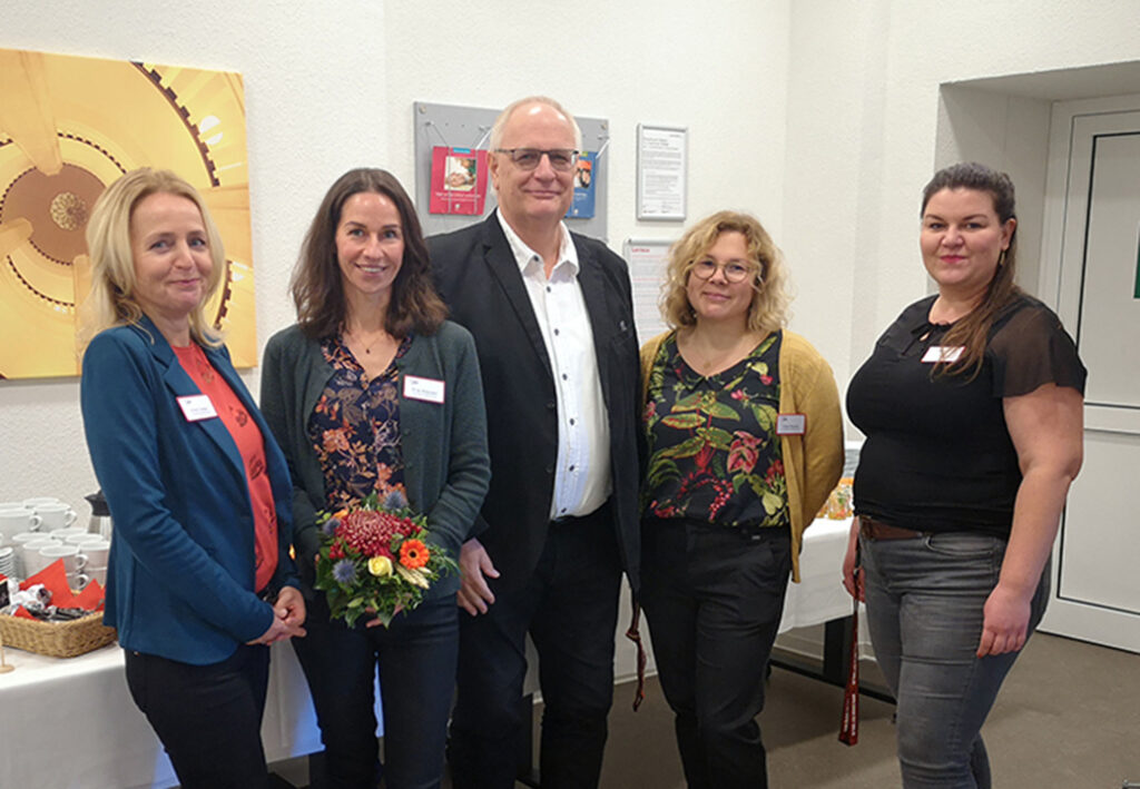 Gruppe von fünf Personen in einem Raum mit einem Tisch Hintergrund