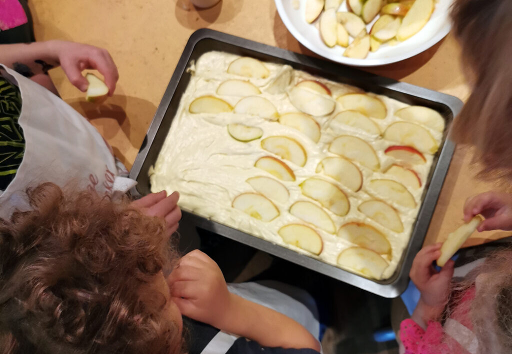Kinder dekorieren Kuchen mit Apfelscheiben