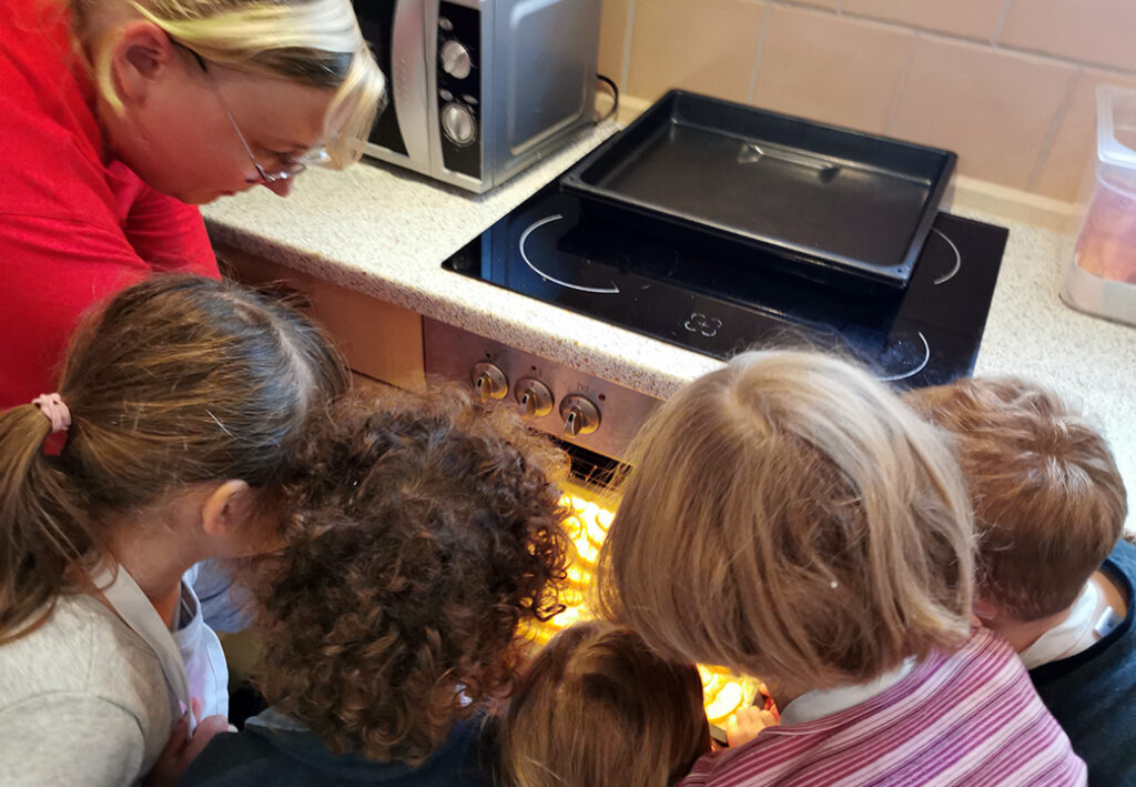 Gruppe von Kindern und Erwachsenem schaut in den Ofen