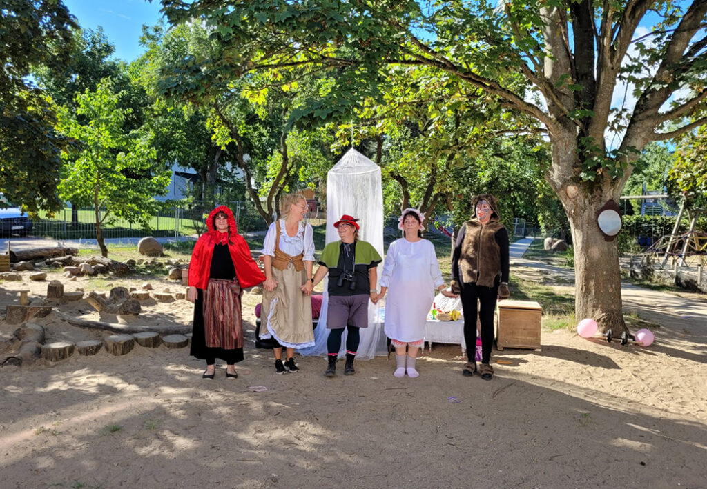 F&uuml;nf Menschen stehen in einem Kreis und sind in M&auml;rchenkost&uuml;men gekleidet.