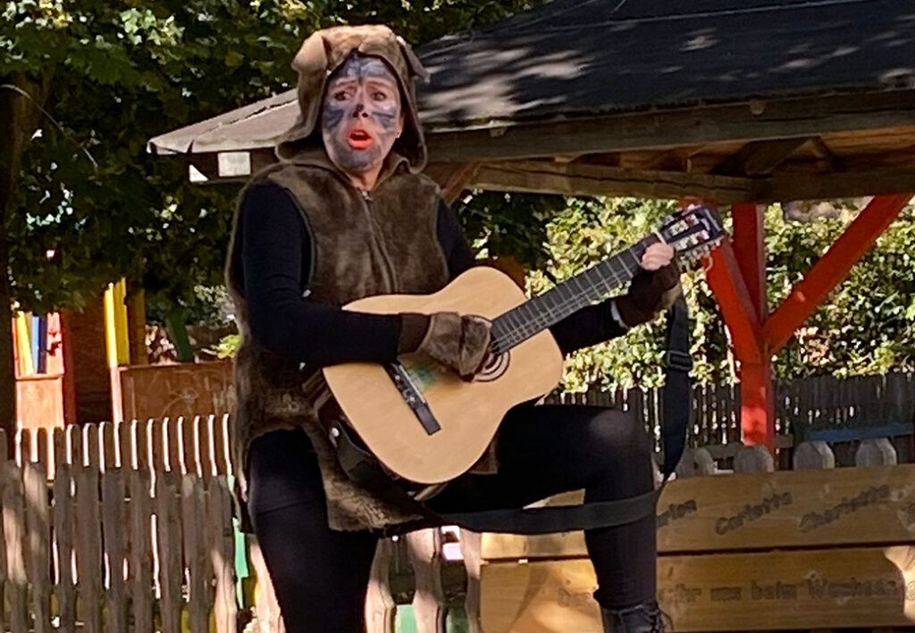 Person in Tierkost&uuml;m spielt Gitarre im Freien