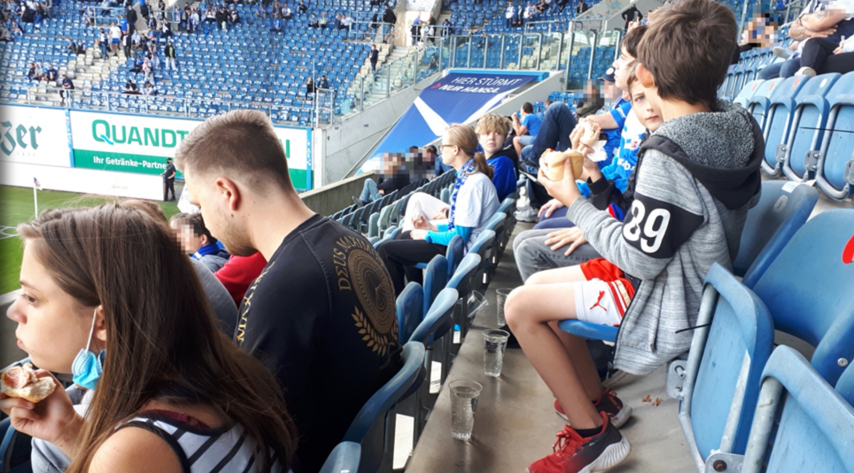 Menschen im Stadion bei einem Fußballspiel mit Essen in der Hand