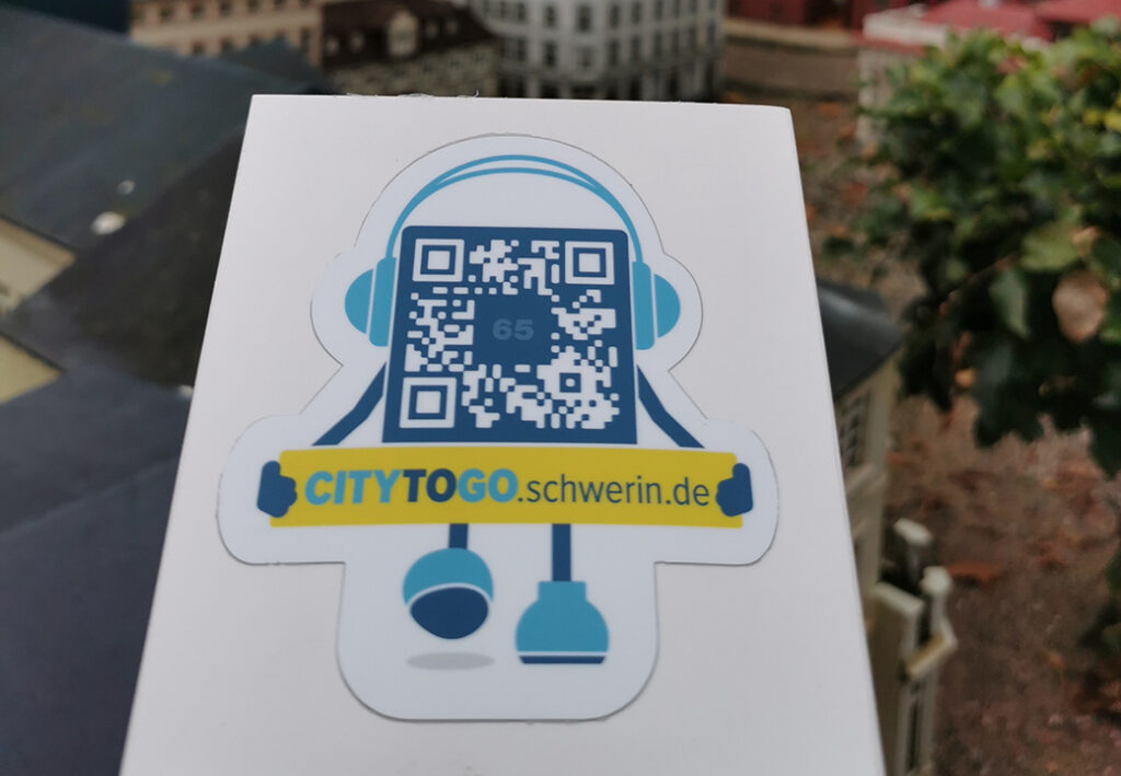Ein Aufkleber mit einem stilisierten Roboter, der einen QR-Code in der Mitte hat.