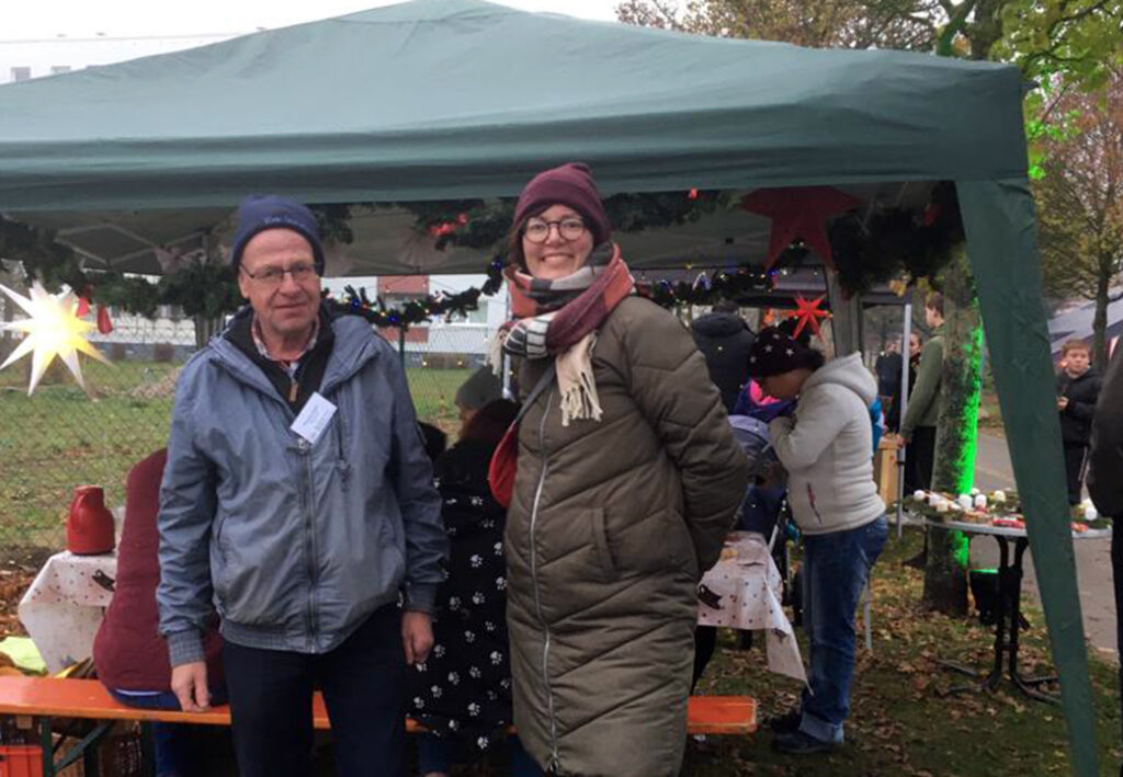 Zwei Personen bei einer Veranstaltung im Freien unter einem Zelt.