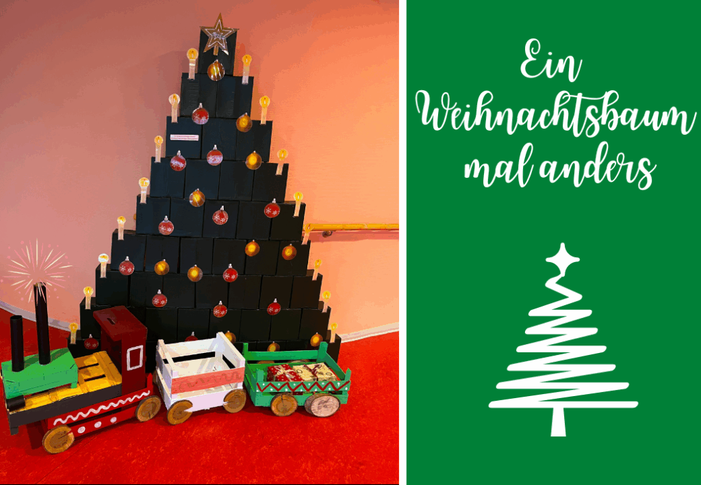 Ein alternativer Weihnachtsbaum aus gestapelten schwarzen Kisten, dekoriert mit Kugeln und Lichtern, neben einem bunten Spielzeugzug.