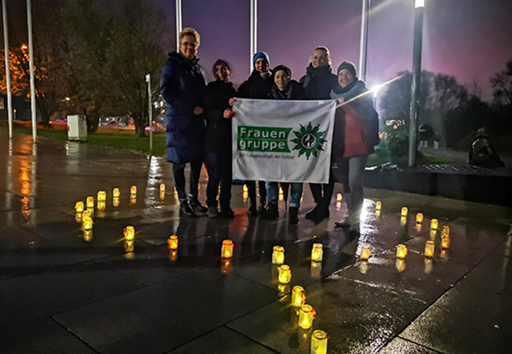 Gruppe von Menschen bei Nacht mit Fackeln um einen Banner stehend