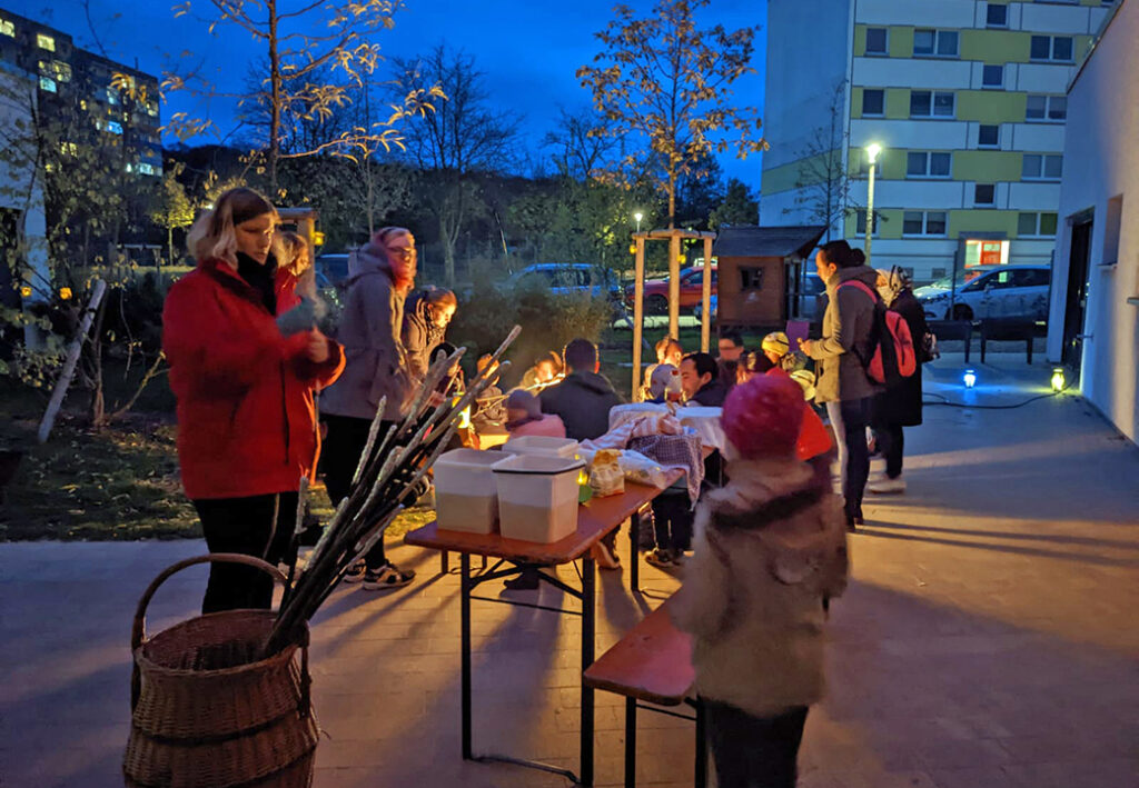 Personen bei einem Abendtreffen im Freien um ein Lagerfeuer.
