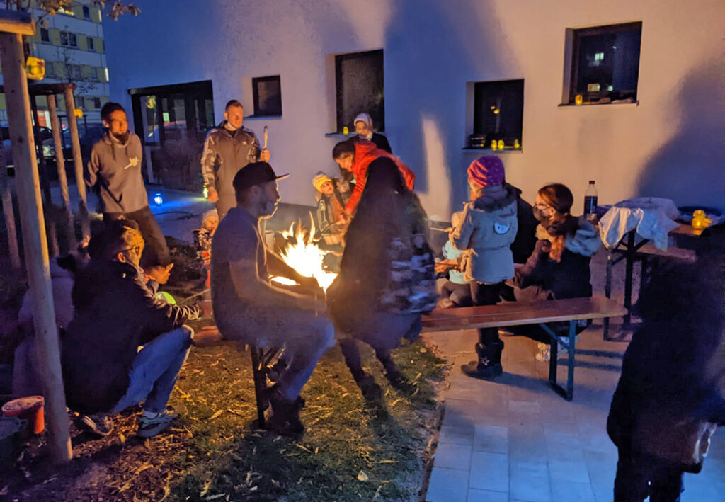 Gruppe von Menschen bei einem Lagerfeuer am Abend im Freien