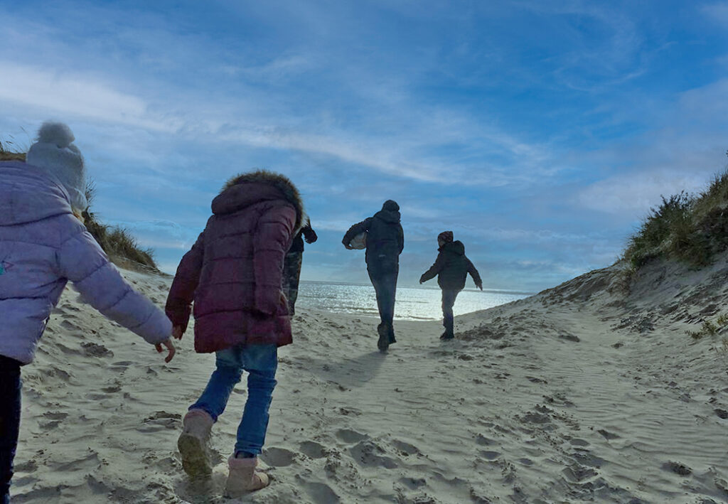 Eine Gruppe von Menschen spaziert im Winter am Strand entlang.