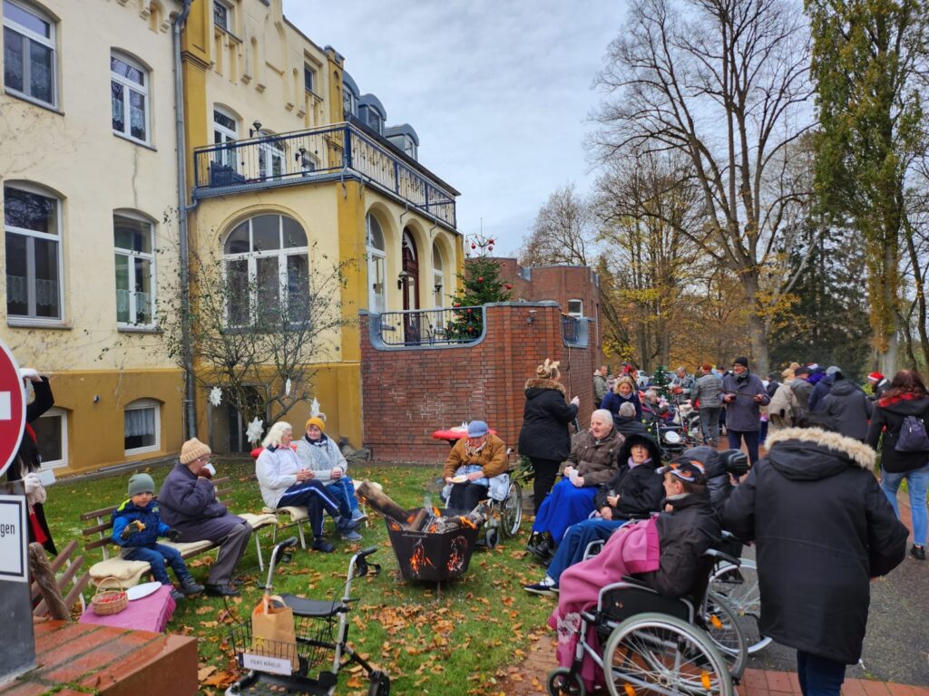 Menschen sitzen drau&szlig;en vor einem alten gelben Geb&auml;ude