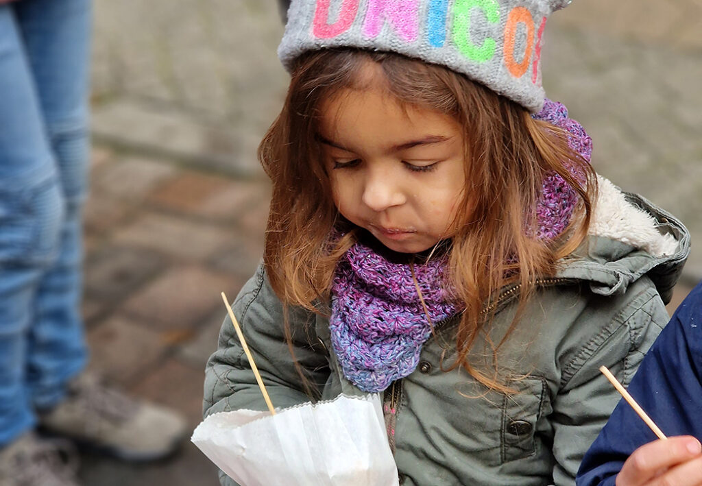 Kind mit Winterkleidung isst drau&szlig;en einen Snack