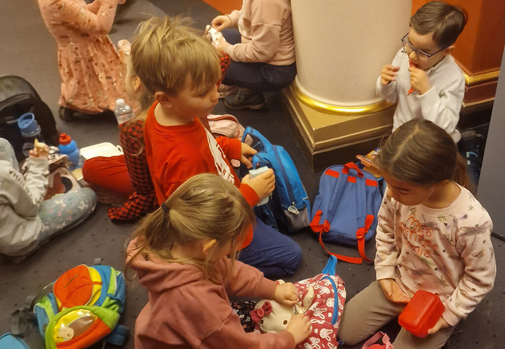 Kinder sitzen auf dem Boden mit Rucks&auml;cken