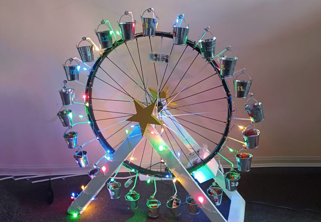 Ein dekoratives Rad mit kleinen Eimern und bunten Lichtern.