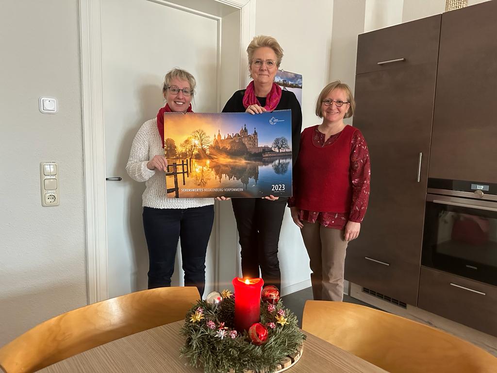 Drei Frauen halten einen großen Kalender.