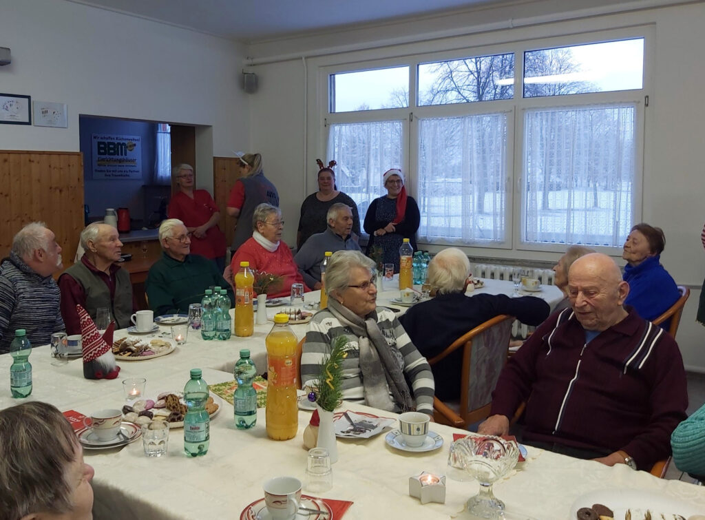 Menschen sitzen an einem Tisch bei einer Weihnachtsfeier