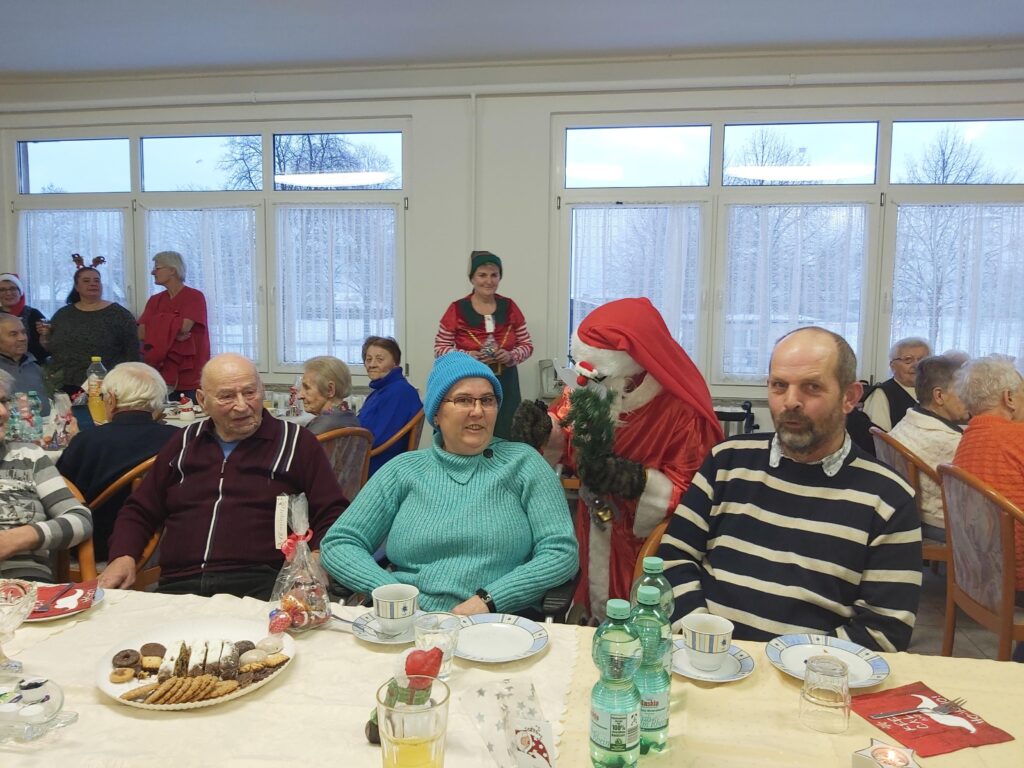 Personen bei einer Weihnachtsfeier in einem Gemeinschaftsraum.