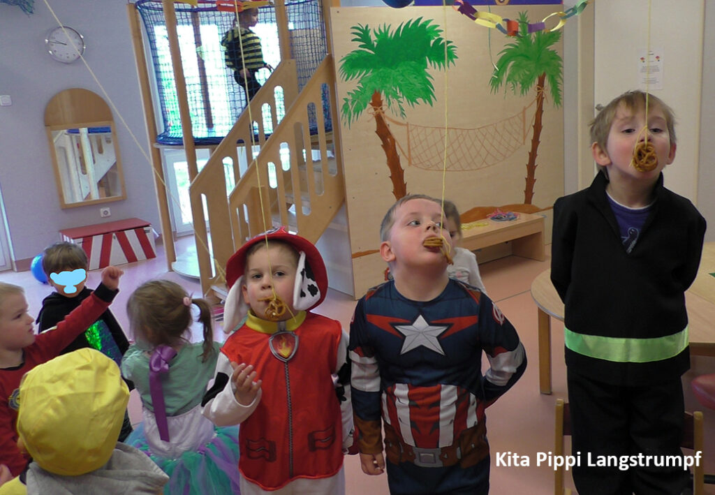 Kinder in Faschingskost&uuml;men spielen ein Spiel in einer Kita.