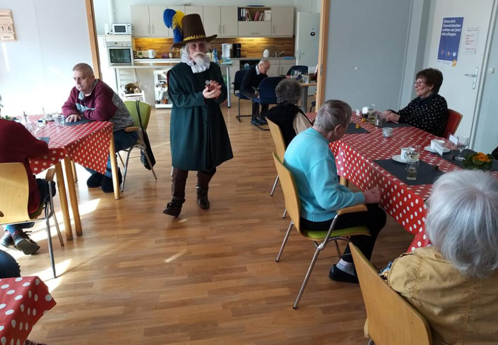 Menschen in einem Gemeinschaftsraum mit einem verkleideten Darsteller.