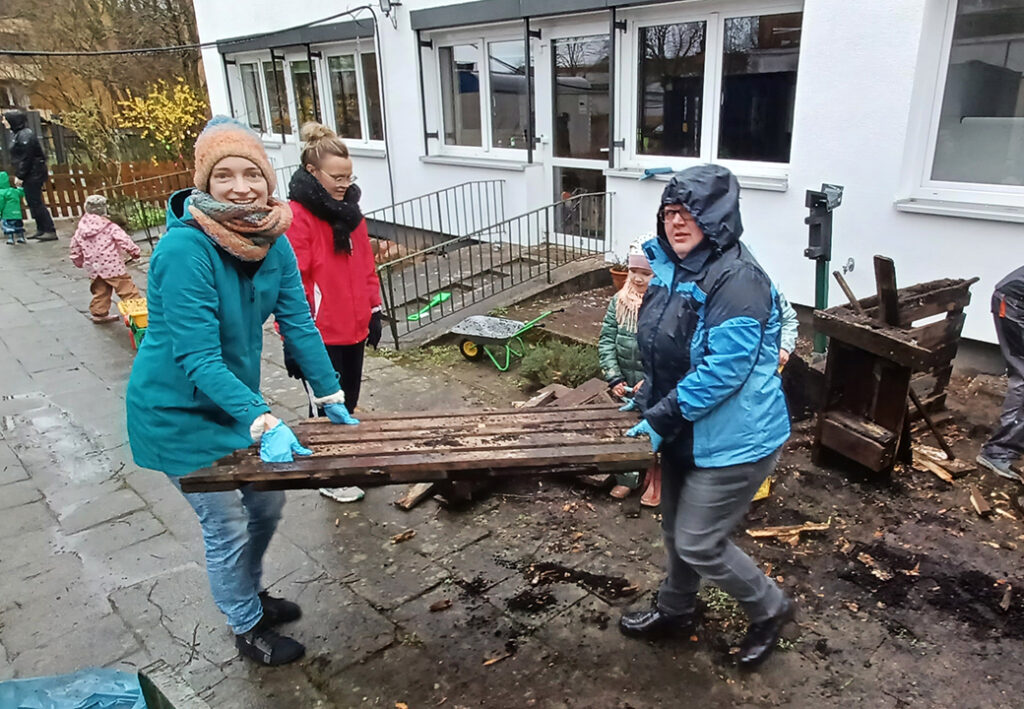 Menschen beim Tragen von Holzbrettern im Freien.