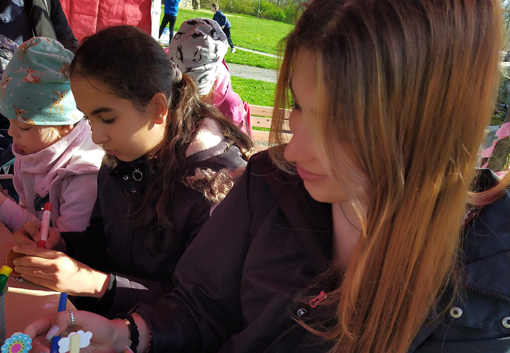 Kinder und Jugendliche bei einer Bastelaktivit&auml;t im Freien