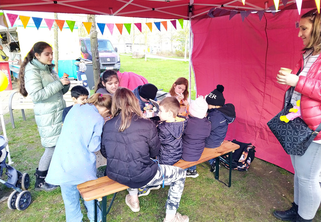 Kinder und Erwachsene unter einem Pavillon bei einer Veranstaltung.